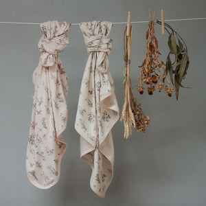 Two swaddle blankets tied and hanging from rope. Meadow print.