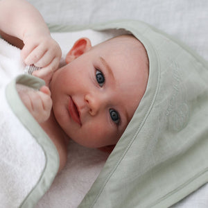 Close up of baby with sage coloured organic hooded towel